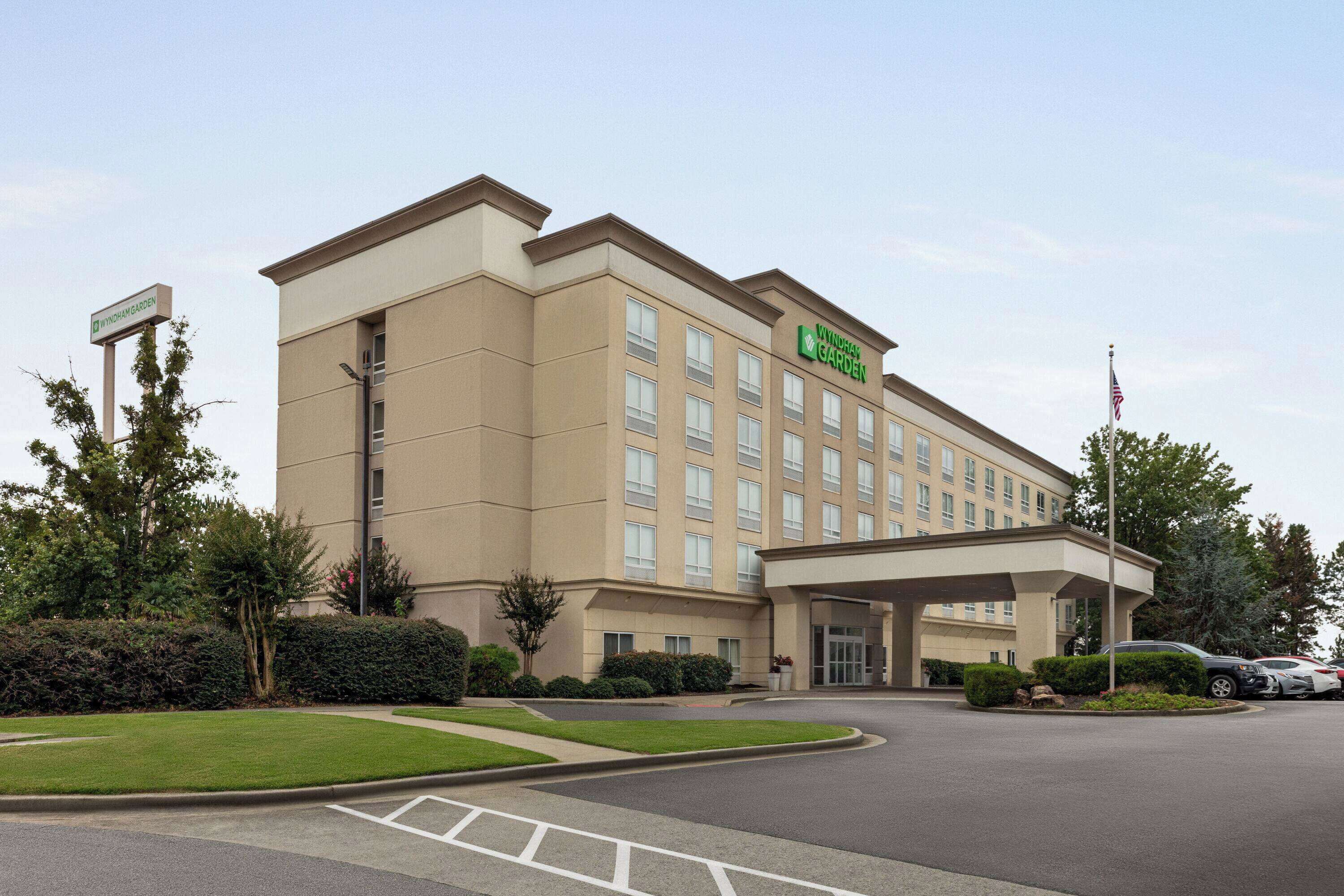 A hotel with a large entrance, multiple floors, and a well-maintained lawn area.