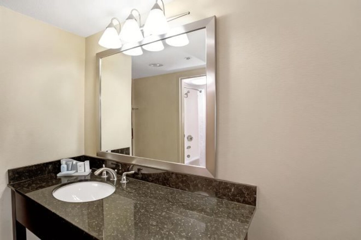 A bathroom with a sink, mirror, and overhead lights.