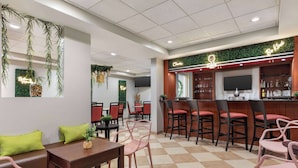 A restaurant with a bar area, seating arrangements, and a green wall with hanging plants.