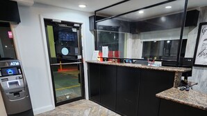 Un moderno vestíbulo de hotel con un cajero automático, una recepción y vistas a la calle.
