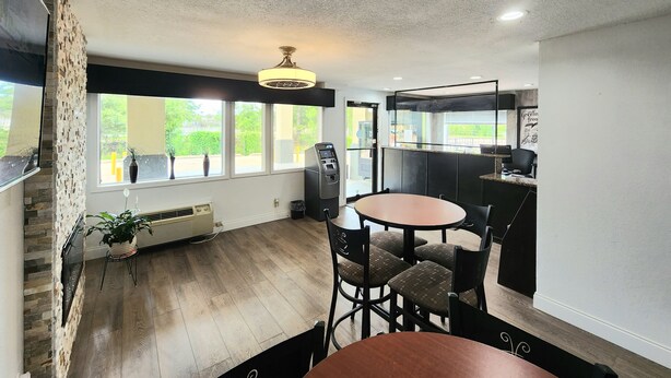 Una cocina moderna con estufa integrada, un comedor con mesa redonda y sillas, y ventanas amplias que ofrecen vistas al exterior.