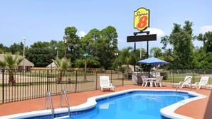 Una piscina con sillones de descanso y un cartel de Super 8.
