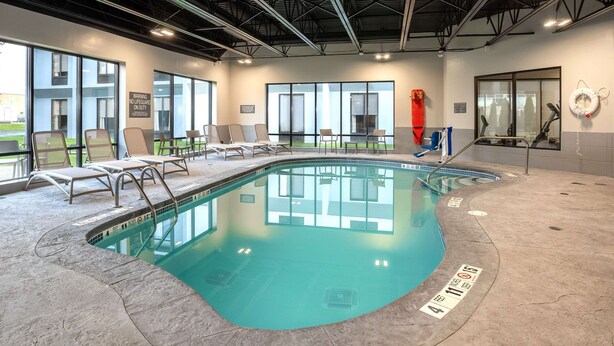 An indoor swimming pool with clear water, lounge chairs, and a lifeguard stand. - Comfort Inn & Suites Buffalo Airport (Buffalo)