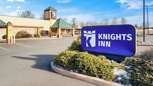 A Knights Inn sign in front of a building with a green roof and stone facade.