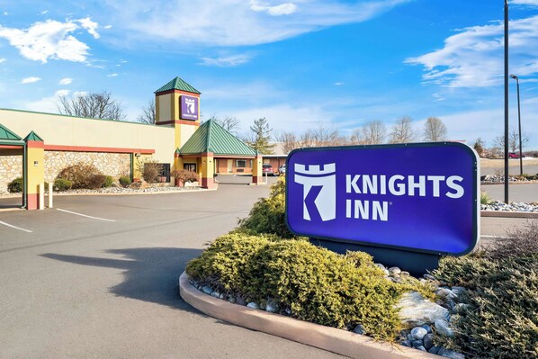 A Knights Inn sign in front of a building with a green roof and stone facade.