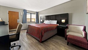 A hotel room with a bed, a desk, a chair, and a nightstand.