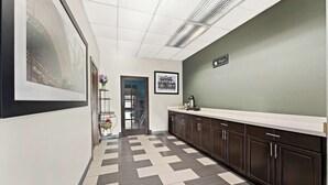 A hallway with patterned flooring, a reception desk, framed pictures on the walls, and a sign above the counter.