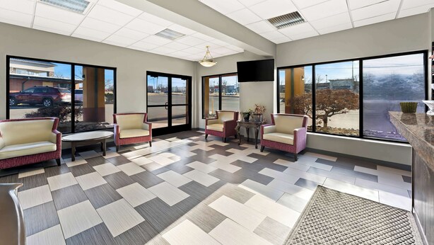 A spacious lobby with a checkered floor, comfortable seating, large windows, and a flat-screen TV.