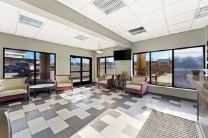 A spacious lobby with a checkered floor, comfortable seating, large windows, and a flat-screen TV.