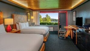 Une chambre d’hôtel avec deux lits, un bureau, une télévision et une vue sur un lac.