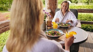 Two people dining outdoors at a wooden table with a salad and orange juice. - Thermen Bad Nieuweschans (Bad Nieuweschans)