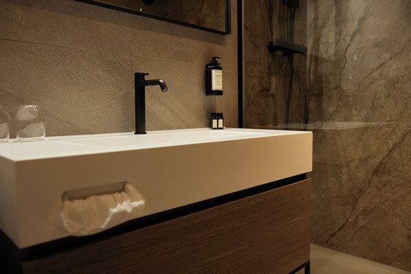 A modern bathroom with a white sink, black faucet, and a marble wall. - Thermen Bad Nieuweschans (Bad Nieuweschans)