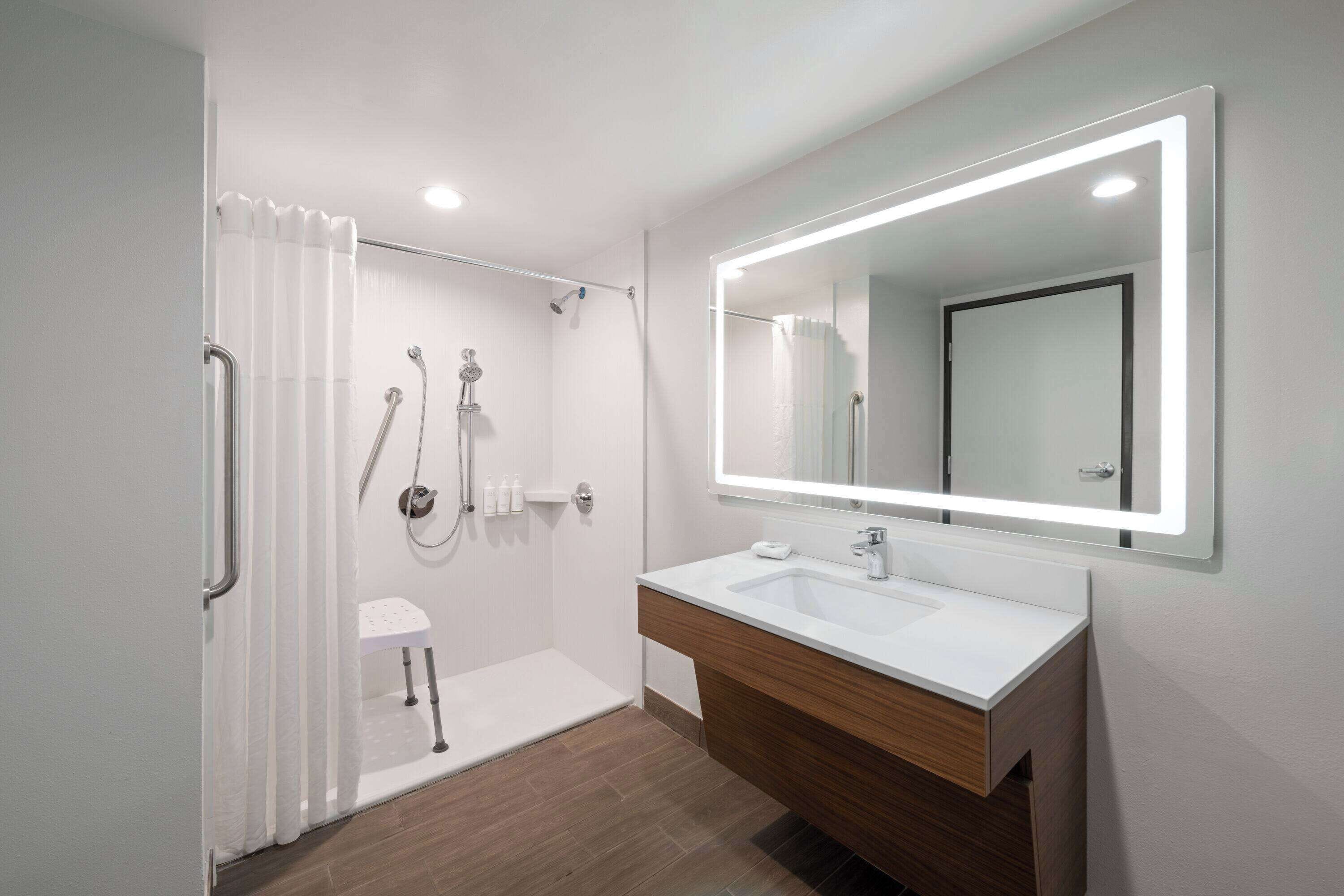 A modern bathroom with a walk-in shower, a vanity with a mirror, and a toilet.