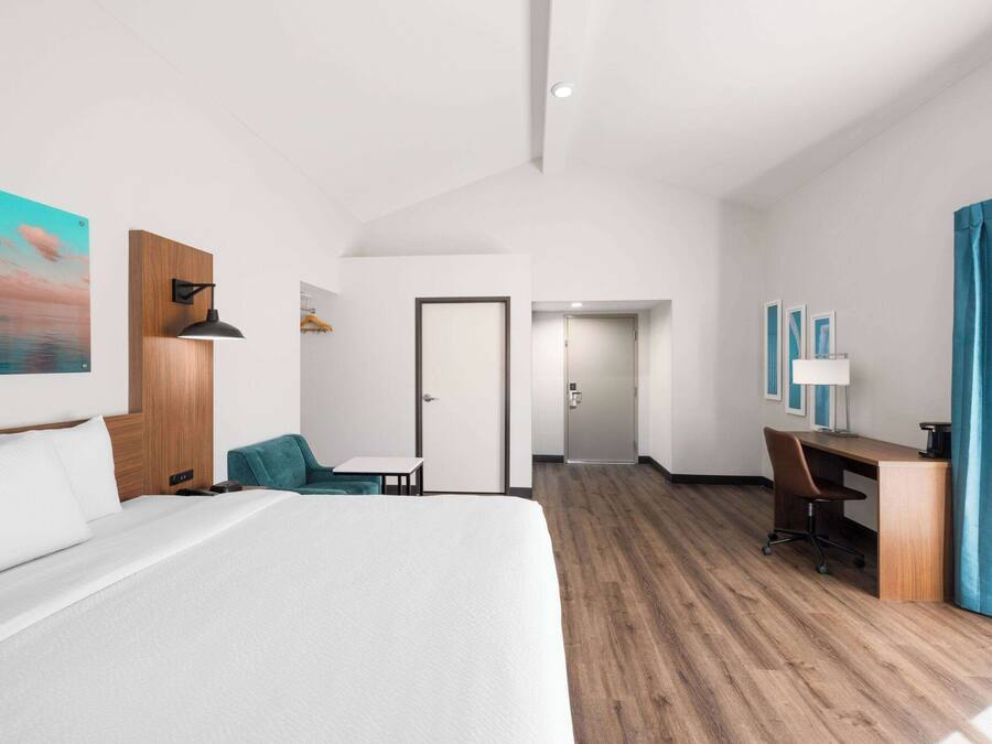 Una habitación de hotel moderna con una cama grande, un escritorio, una silla y vistas al pasillo.