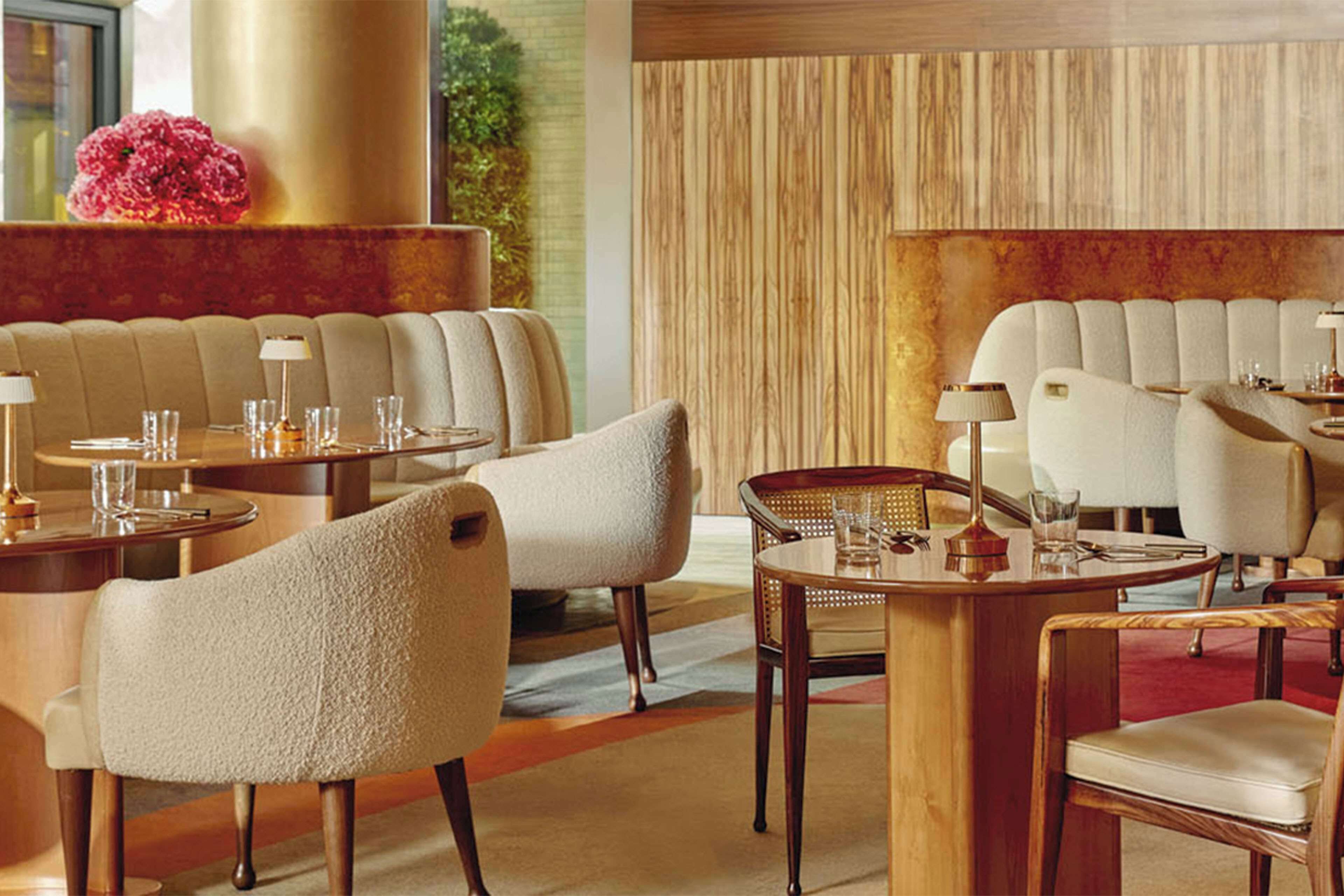 Un hall d’hôtel doté de sièges en cuir, de tables en bois et d’un mur décoratif.