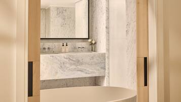 A bathroom with a marble sink, a large mirror, and a bathtub.