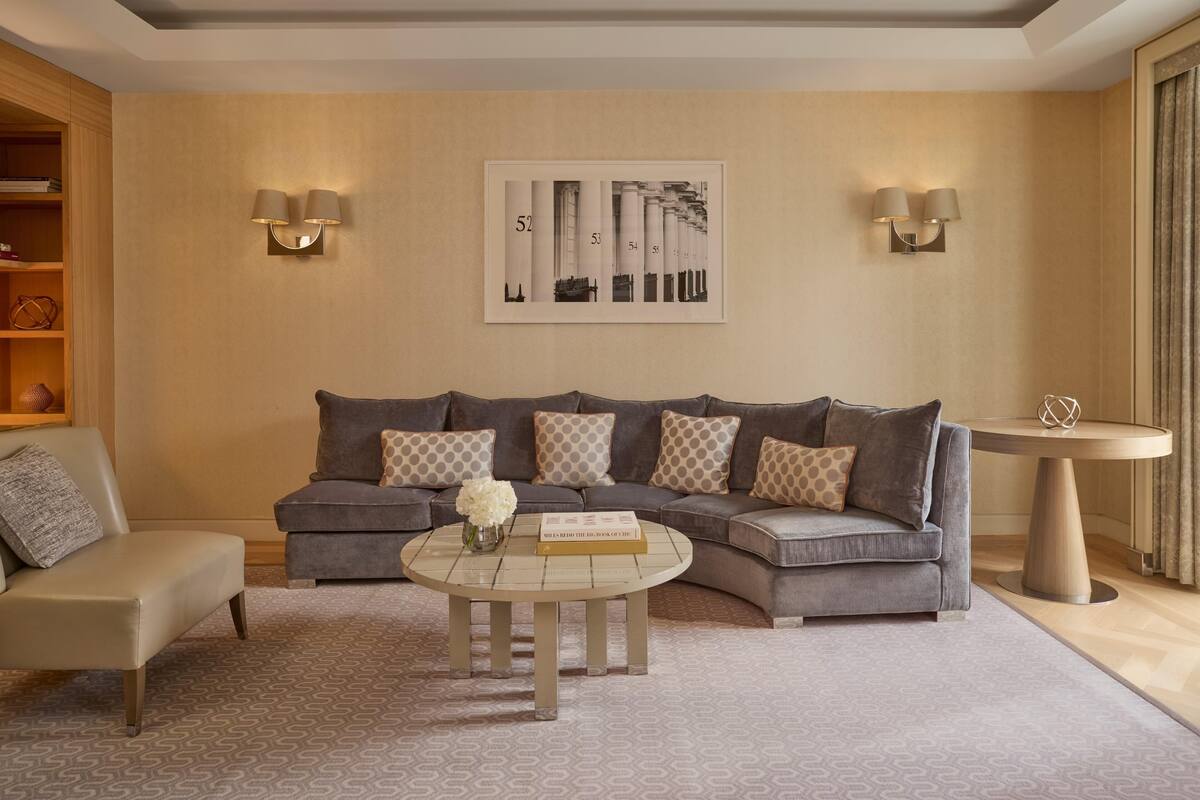 A modern living room with a sectional sofa, a round coffee table, and a framed artwork on the wall.