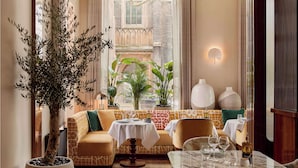A cozy interior with a sofa, a table set for dining, and potted plants. - The Berkeley, Maybourne  (London)