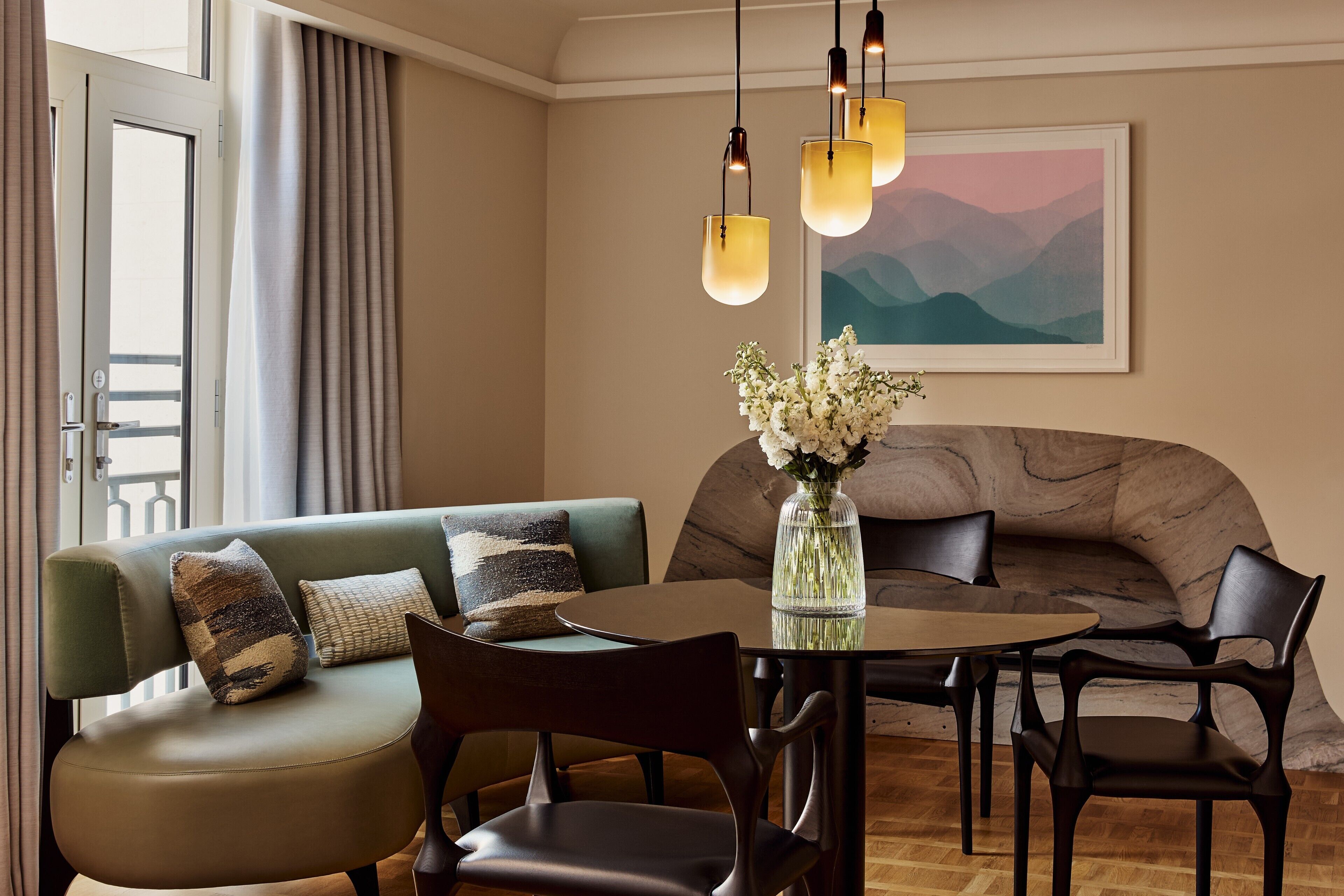 Una sala de estar moderna con un sofá, sillas, una mesa de comedor y un jarrón con flores.