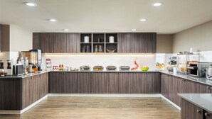 Una cocina moderna con armarios de madera oscura, una isla central y una variedad de electrodomésticos y recipientes de almacenamiento.