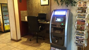A self-service ATM with a digital display, a computer desk, and a chair. - Americas Best Value Inn & Suites Ft. Collins E at I-25 (Fort Collins)