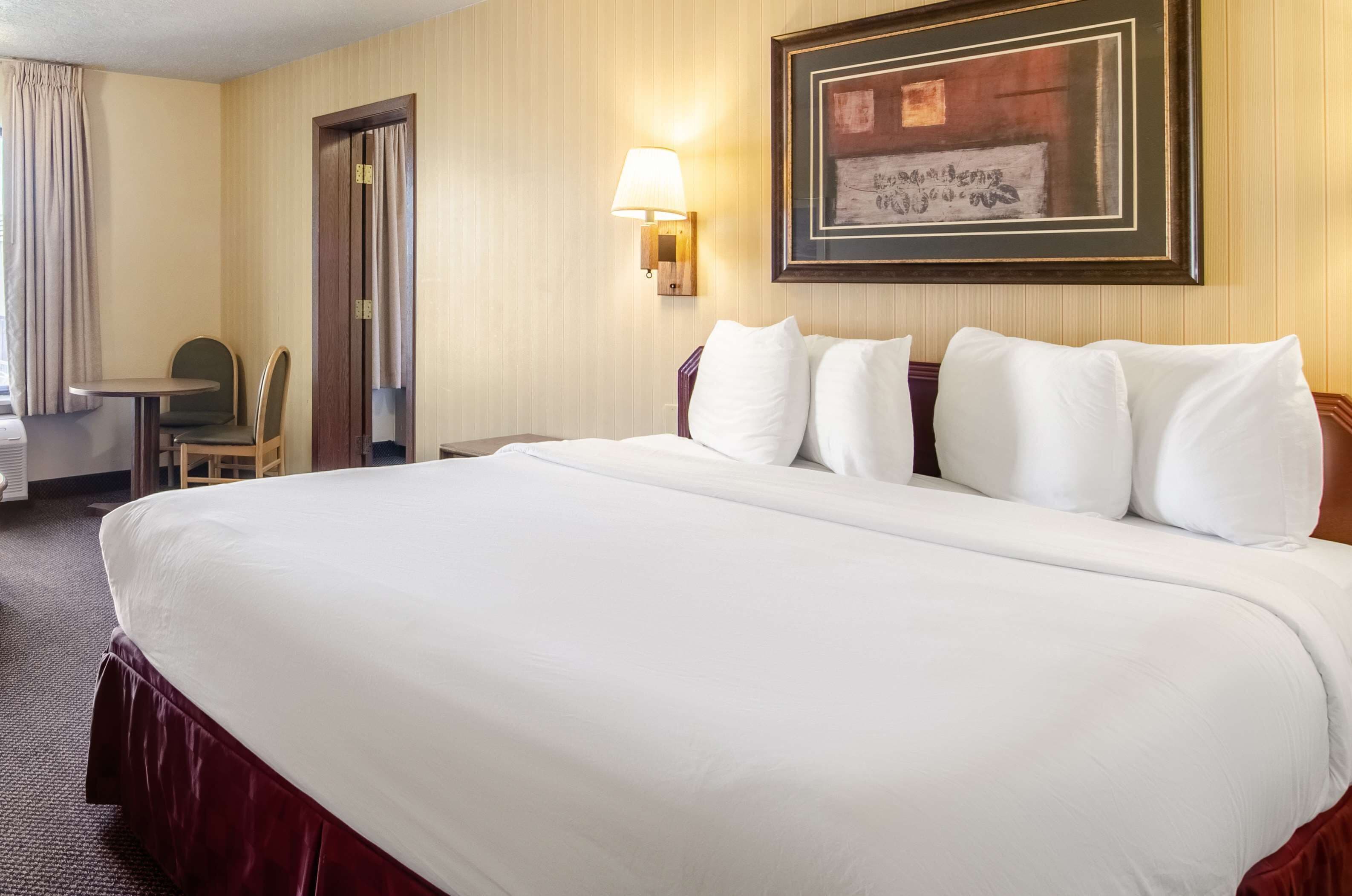 Une chambre d’hôtel avec un grand lit, un bureau, une chaise et une lampe fixée au mur.