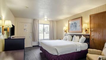 A hotel room with a large bed, a desk, a chair, and a television.