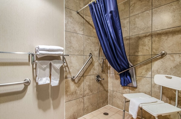 Un espace douche avec un rideau bleu, des barres d’appui et un banc blanc.