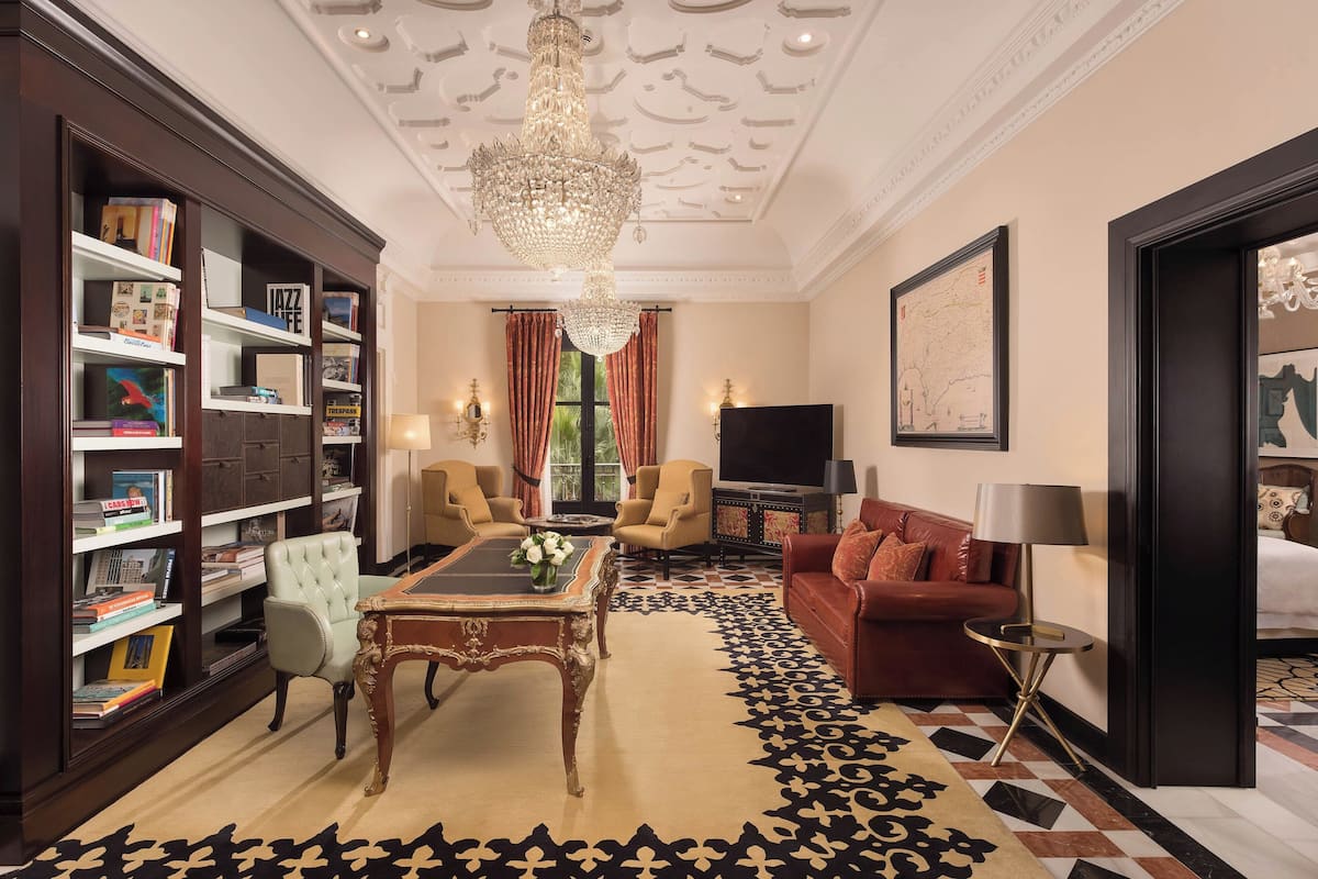 A well-furnished living room with a chandelier, bookshelves, a sofa, and a television.