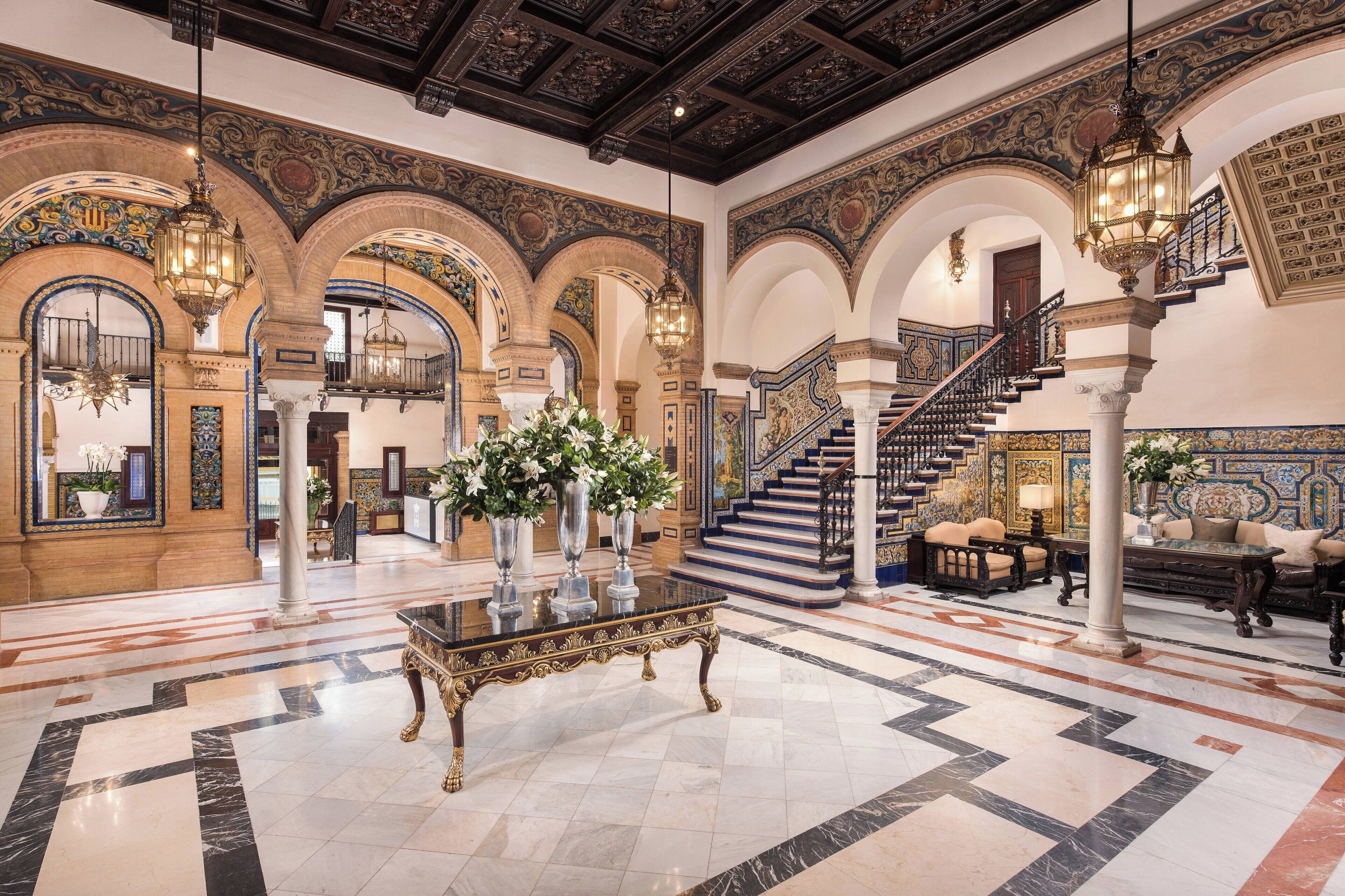 A grand lobby with ornate arches, a marble floor, and a staircase.