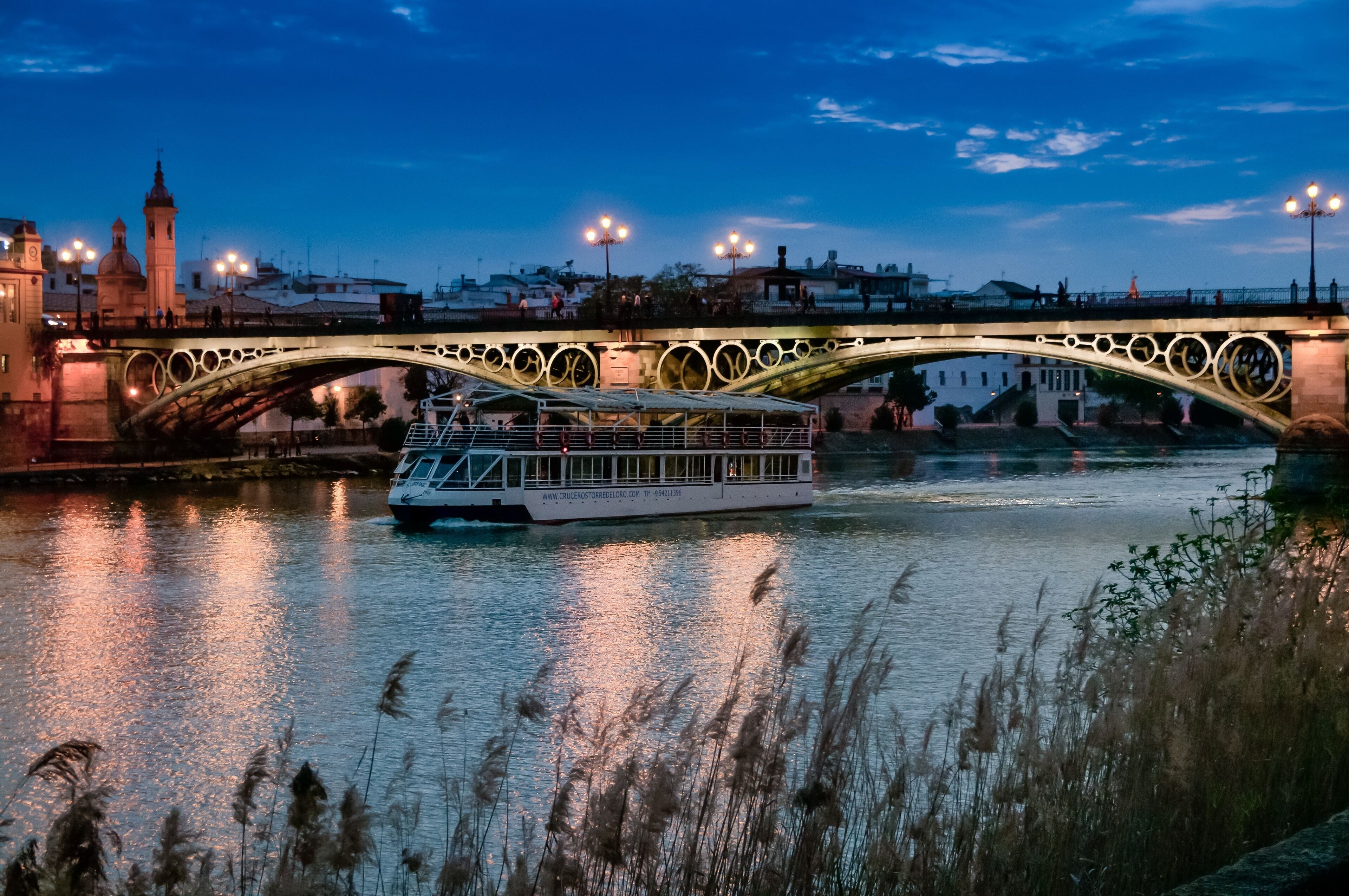 Un río con un bote y un puente con arcos decorativos.