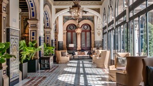 A spacious lobby with a checkered floor, large windows, and a central seating area with sofas and armchairs.
