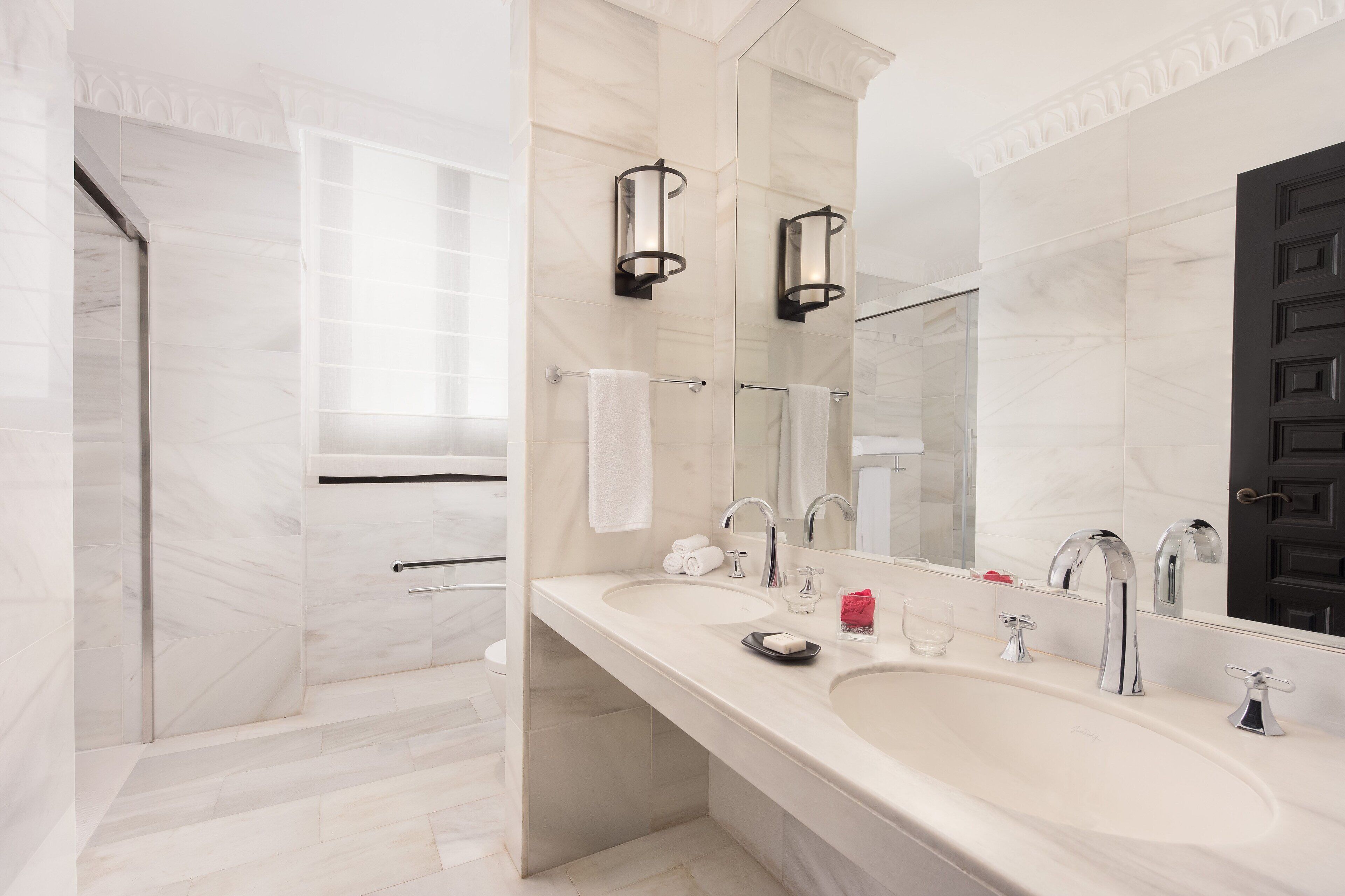 Un baño moderno con un espejo grande, dos lavabos y una zona de ducha.