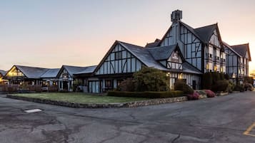 A traditional Tudor-style building with a symmetrical facade, large windows, and a stone foundation.