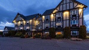 Un grand hôtel à plusieurs étages, de style architectural traditionnel, doté d’un hall d’entrée imposant et d’aménagements paysagers bien entretenus.