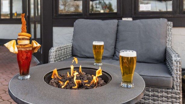 Une table ronde avec un foyer au centre, entourée de trois verres de bière.