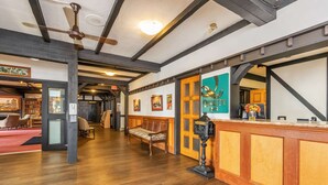Un hall d’entrée spacieux avec un plancher en bois, un comptoir d’accueil, un banc et un ventilateur de plafond.