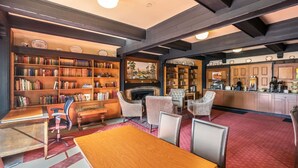 Une bibliothèque spacieuse, dotée d’étagères, d’une cheminée et d’un coin repas avec une table et des chaises en bois.