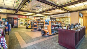 Une boutique de vente de boissons alcoolisées, avec des étagères remplies de bouteilles et une pancarte indiquant « PAQUET DE 15 ».