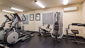 Ein Fitnessraum mit verschiedenen Trainingsgeräten, darunter Laufbänder, eine Gewichtbank und ein Kabelzuggerät.