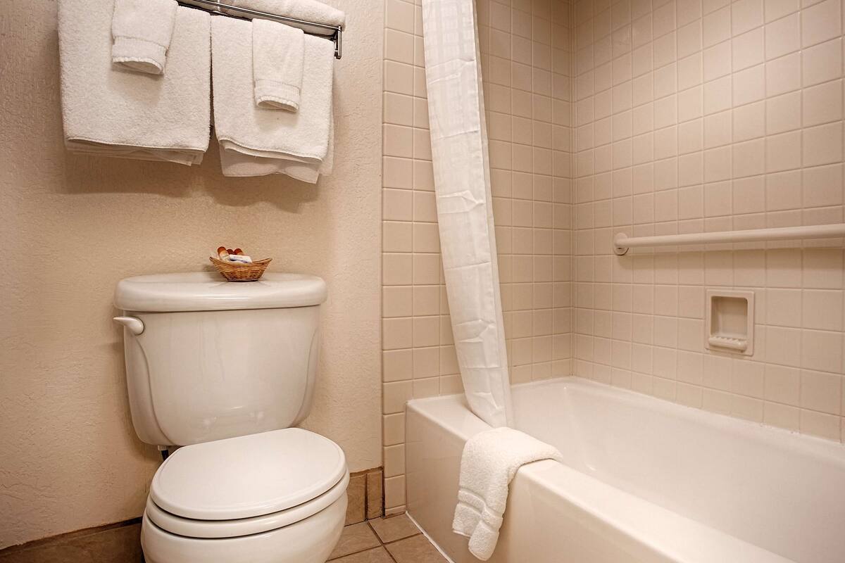 A bathroom with a toilet, a bathtub, and a shower curtain.