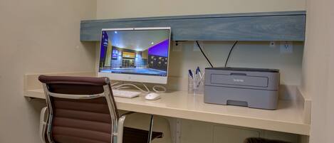 A desk with a computer monitor, printer, and chair.