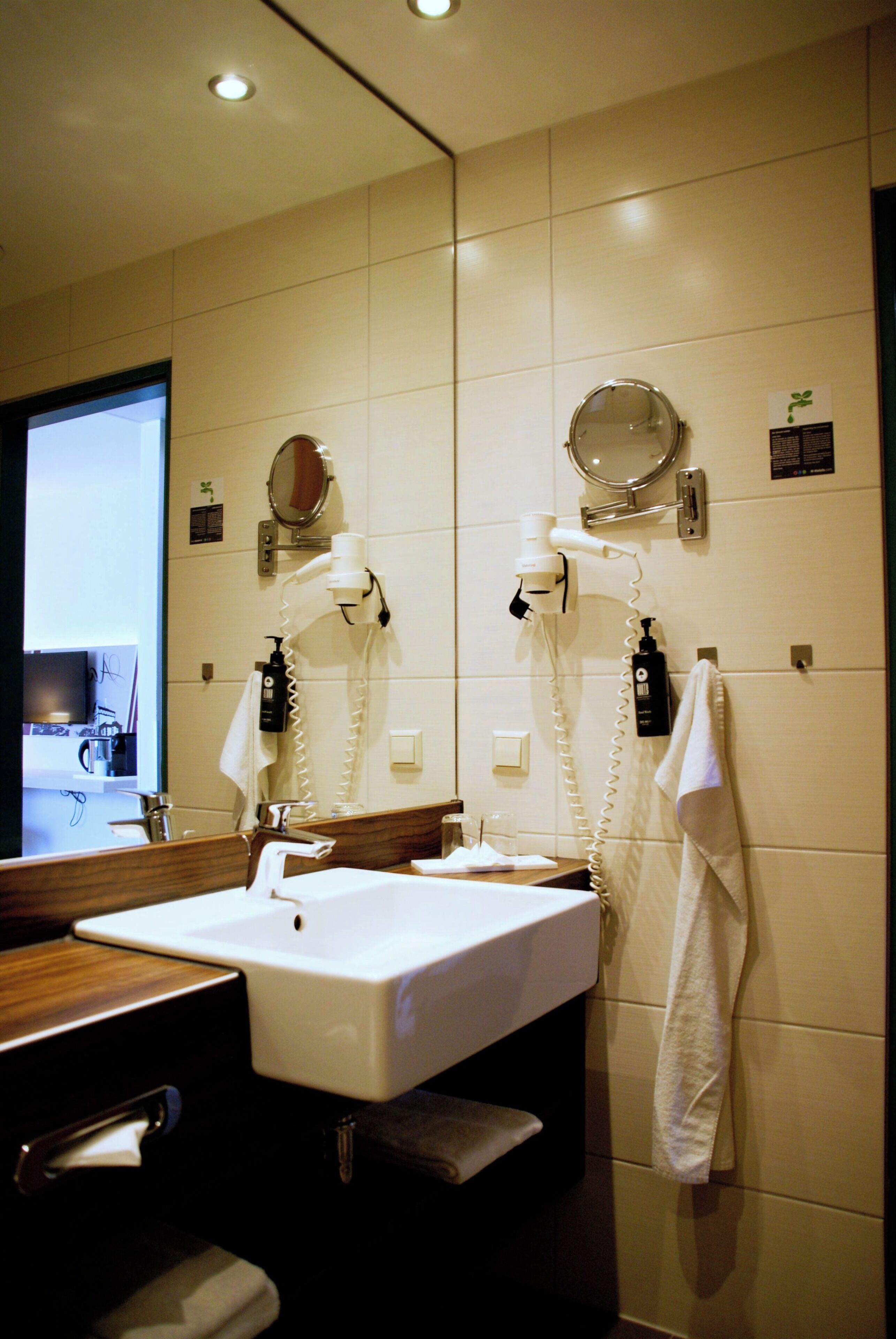 Un baño con lavamanos, espejo, toallero y secador de pelo.