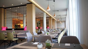 Un restaurant moderne avec de longues tables, des chaises et des luminaires suspendus.
