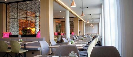 Een modern restaurant met lange tafels, stoelen en hanglampen.