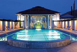 A swimming pool with lounge chairs and a covered area with a roof.