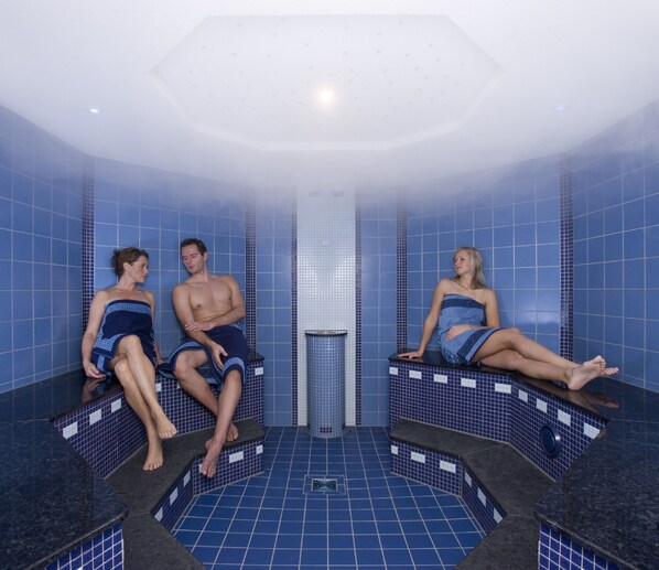 Een sauna met blauwe betegelde wanden en banken.