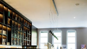 Un área de bar moderna con una barra larga, varios taburetes y una estantería de diseño geométrico.