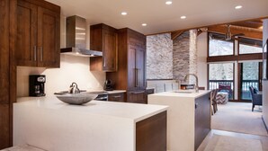 Una cocina moderna con una isla grande, armarios de madera y una pared de acento de piedra.
