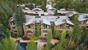 Un hotel de varios pisos con balcones, piscina y zonas verdes alrededor.
